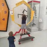 little girl and toddler playing with a big clock at the Cape Town Science Center