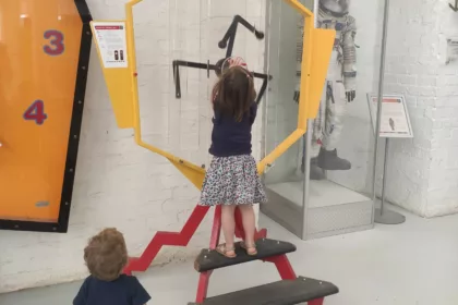 little girl and toddler playing with a big clock at the Cape Town Science Center