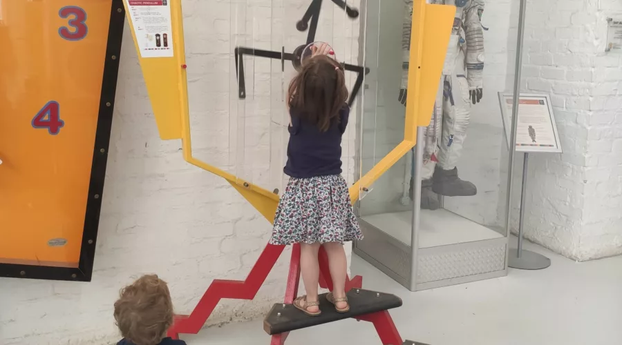 little girl and toddler playing with a big clock at the Cape Town Science Center